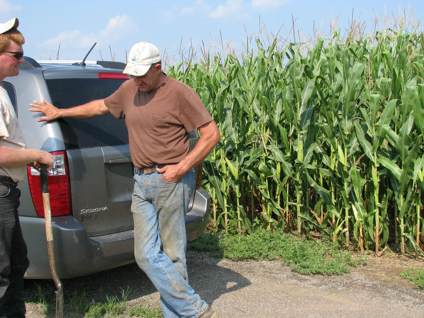 Two men talking beside a tall Pro-Soil treated corn field in Pennsylvania